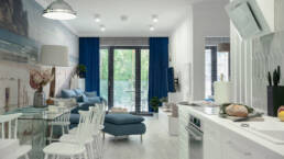 Jasny salon apartamentu Sea & Forest z dużymi przeszkleniami, naturalnym światłem i błękitnymi akcentami &ndash; fotografia wnętrz premium Międzyzdroje